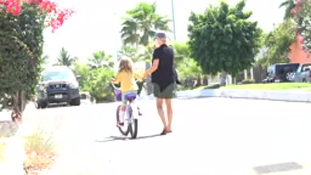 LOS CABOS MEXICO-2020: Mother Holding Bike To Help Teach Her Child How To Ride