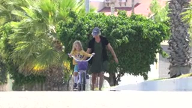 LOS CABOS MEXICO-2020: Woman Walks With Young Girl As She Rides Her Bike