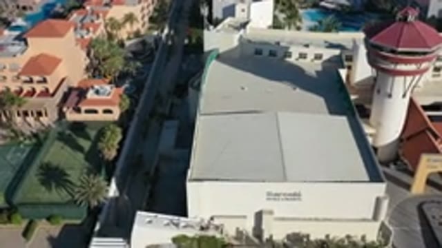 LOS CABOS MEXICO-2020: Fly Over View Of Resort Style Building With Tower And Palm Trees