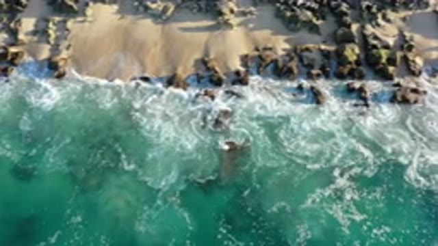 LOS CABOS MEXICO-2020: White Waves Crashing On Rocky Reef Jetty Sandy Beach
