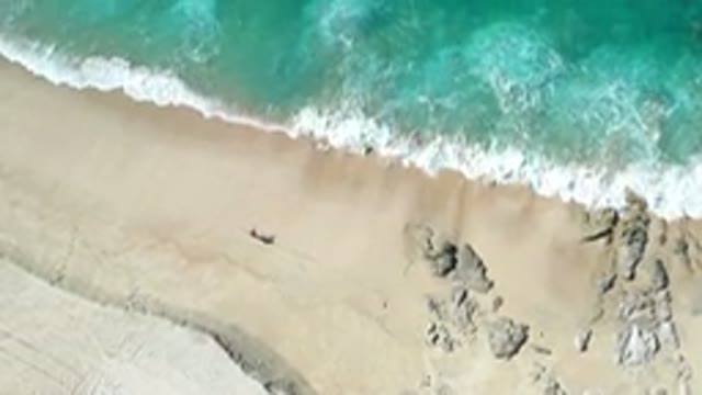 LOS CABOS MEXICO-2020: Person Walking Beach Admiring Ocean Waves Splashing Rocks