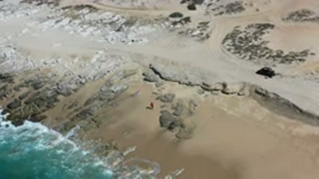 LOS CABOS MEXICO-2020: Waves Crashing On A Rocky Beach Near A Man In Red