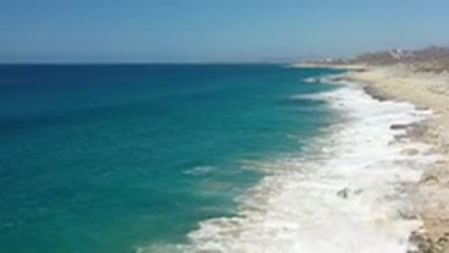 LOS CABOS MEXICO-2020: Waves From A Blue Sea Wash Up On A Rocky Beach With