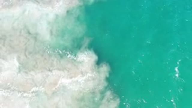 LOS CABOS MEXICO-2020: Green Ocean Waves Mix With White Sand Forming Dusty Cloud
