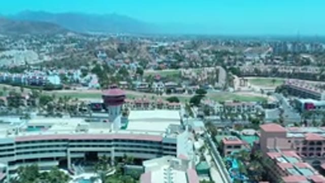 LOS CABOS MEXICO-2020: Flyover Shot Of A Hazy Green Valley With Modern Buildings