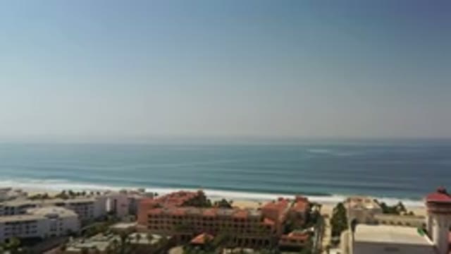 LOS CABOS MEXICO-2020: Hazy Sky Over Blue Ocean As Waves Crash Onto Beach Near