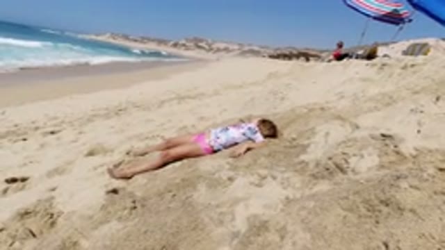 LOS CABOS MEXICO-2020: Small Child Laying On The Sand At The Beach Coastline