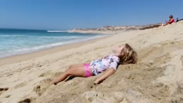 LOS CABOS MEXICO-2020: View Of A Little Girl Laying On The Sand At The Beach And