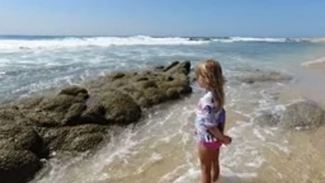 LOS CABOS MEXICO-2020: Child At The Beach Standing In Front Of Large Rocks In