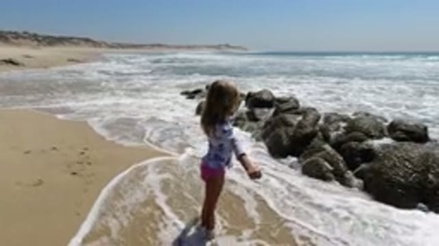 LOS CABOS MEXICO-2020: Little Girl Dancing Around In The Ocean With Her Parents
