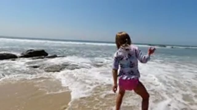 LOS CABOS MEXICO-2020: A Little Girl With Her Dog Playing In The Ocean Waters