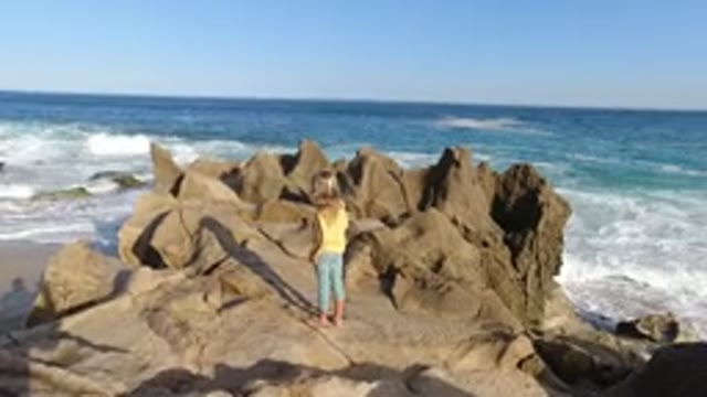 LOS CABOS MEXICO-2020: A Little Girl in a Yellow Dress Stands Near Beach Water