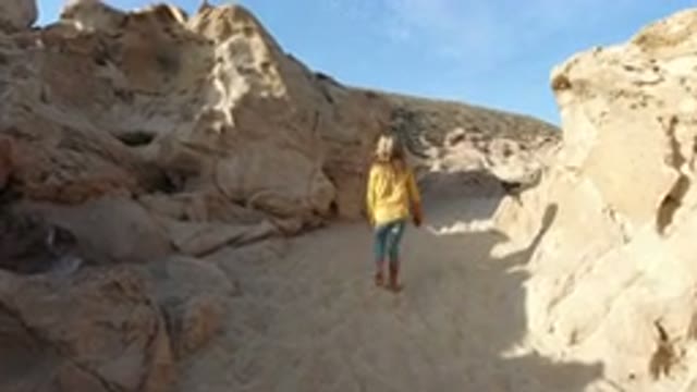 LOS CABOS MEXICO-2020: Girl In Yellow Coat Walking On Sandy Ground Amid Rocks