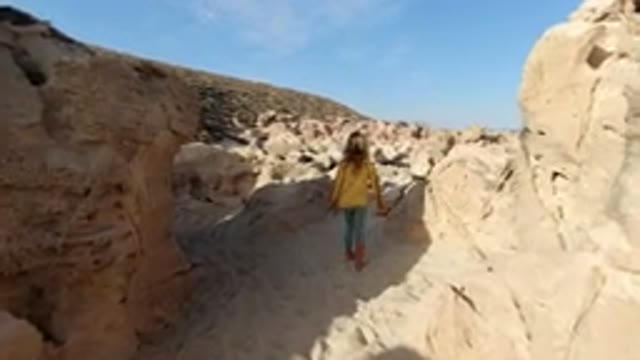 LOS CABOS MEXICO-2020: Child With Long Hair Walk On Sand In Between Rocks Of A