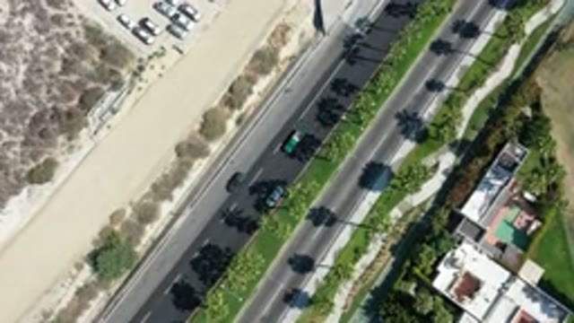 LOS CABOS MEXICO-2020: Cars Driving Down A Narrow Street With Palm Trees
