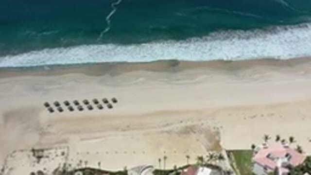 LOS CABOS MEXICO-2020: Rooftops Of Homes Along Sandy Beach As Ocean Waves Crash
