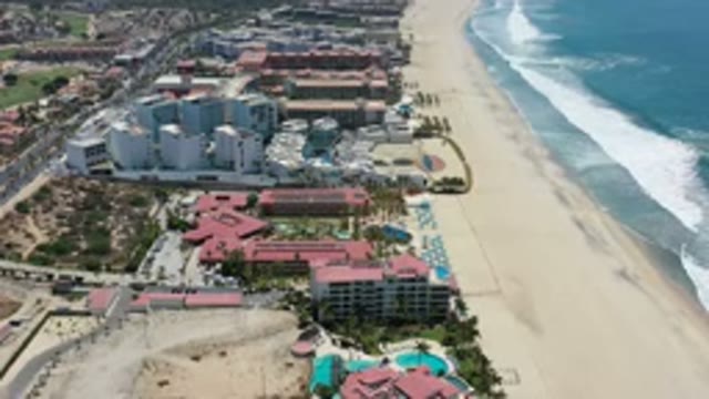 LOS CABOS MEXICO-2020: Waves Crashing Into The Sand Of A Beach Next To A City