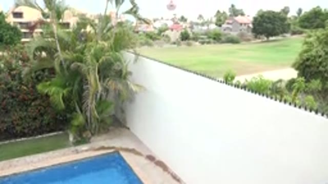 LOS CABOS MEXICO-2020: A Lush Backyard With A Pool Surrounded By A White Stucco