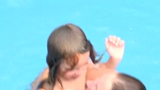 LOS CABOS MEXICO-2020: Mother In Swimsuit With Earrings Hugs Her Child In The Pool