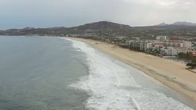 LOS CABOS MEXICO-2020: Waves Crashing Upon The Shore Of A City With Mountains