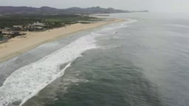 LOS CABOS MEXICO-2020: Soaring Over The Ocean's Waves Lapping Against A Long Beach