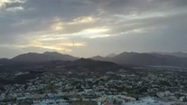 LOS CABOS MEXICO-2020: Sunset And Yellow Clouds Over Beautiful Green Mountains