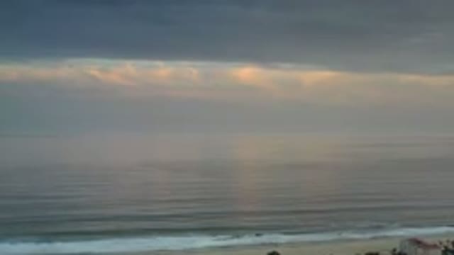 LOS CABOS MEXICO-2020: Ocean Waves Gently Hit Shore Sunset Hidden Behind Dark Clouds