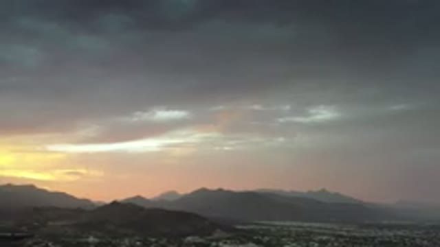 LOS CABOS MEXICO-2020: Yellowish Haze Around Clouds As Sun Rises Over City With Mountains