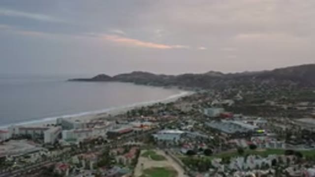 LOS CABOS MEXICO-2020: Cloudy Sky Over Beach With Gentle Waves And City View