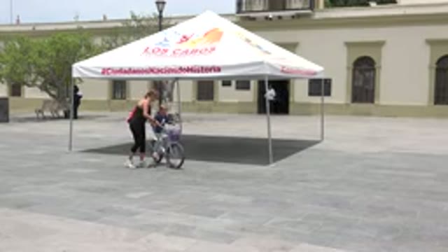LOS CABOS MEXICO-2020: Mother Teaching Her Baby To Ride Bicycle On The Road