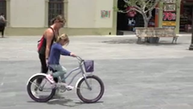 LOS CABOS MEXICO-2020: Cute Little Girl Learning To Ride A Bicycle With Her Mother