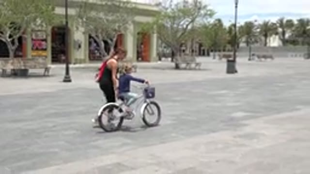LOS CABOS MEXICO-2020: A Woman Teaching A Child To Ride A Bicycle In The Park