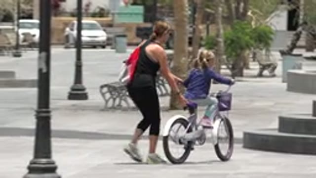 LOS CABOS MEXICO-2020: Mother Holds Bike As Daughter Hops To Climb Steps