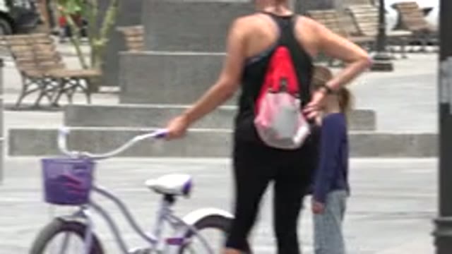 LOS CABOS MEXICO-2020: Woman Holding Bicycle In Public Square With Statue And