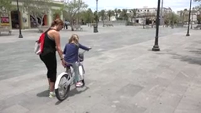 LOS CABOS MEXICO-2020: Woman Helps A Young Girl Ride A Bicycle On A Quiet Day