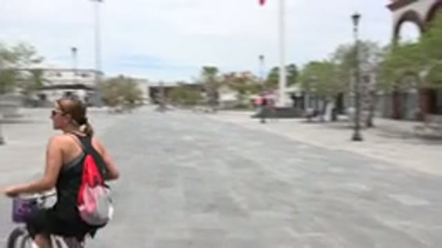 LOS CABOS MEXICO-2020: Lady Wearing A Backpack Rides In A Circle On A Bike In A