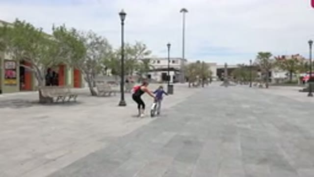 LOS CABOS MEXICO-2020: Woman Helping Child Ride Bike