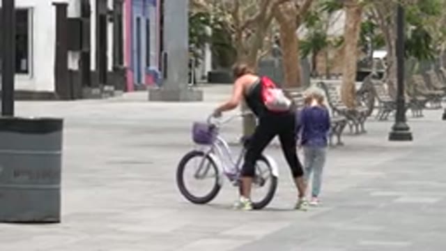 LOS CABOS MEXICO-2020: Woman Helping A Child Pick Up Her Bicycle In An Empty Street
