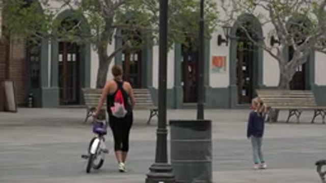 LOS CABOS MEXICO-2020: Adult Walking Slowly With A Bicycle While A Small Child
