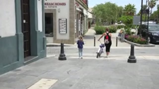LOS CABOS MEXICO-2020: Mother Walking Her Daughter's Bike Across The Road To A