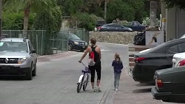 LOS CABOS MEXICO-2020: Small Girls Walks Next To Woman Walking Her Bike On