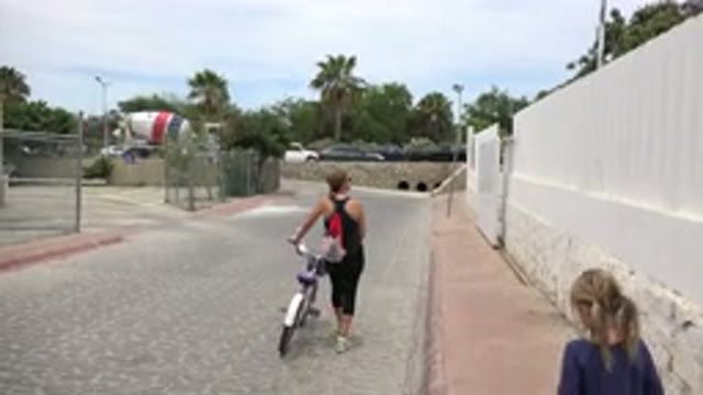 LOS CABOS MEXICO-2020: Mother Looks Up While Walking a Bike with Her Daughter