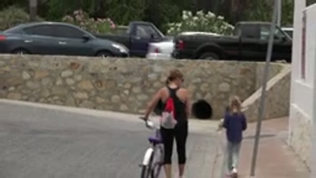 LOS CABOS MEXICO-2020: Woman With Child and Bike Walks Sidewalk Near Road