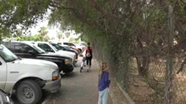 LOS CABOS MEXICO-2020: Girl Walking Behind Woman With Bike On A Sidewalk Next To