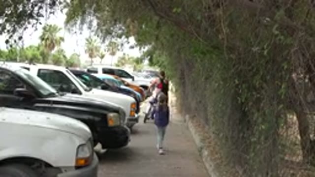 LOS CABOS MEXICO-2020: A Woman And Child Walking Across The Parking Lot With A