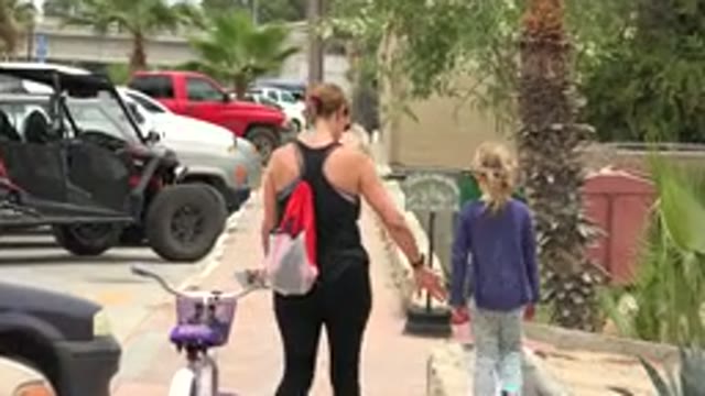 LOS CABOS MEXICO-2020: A Woman Walking With Her Child and Bicycle on a Road