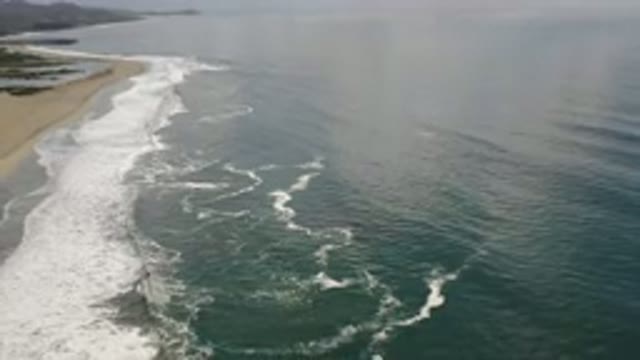 LOS CABOS MEXICO-2020: Blue Waves Breaking On Sandy Beach With Rocky Shore In