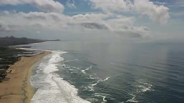 LOS CABOS MEXICO-2020: Waves Crash Onto Sandy Beach With Deep Blue Ocean And Sky