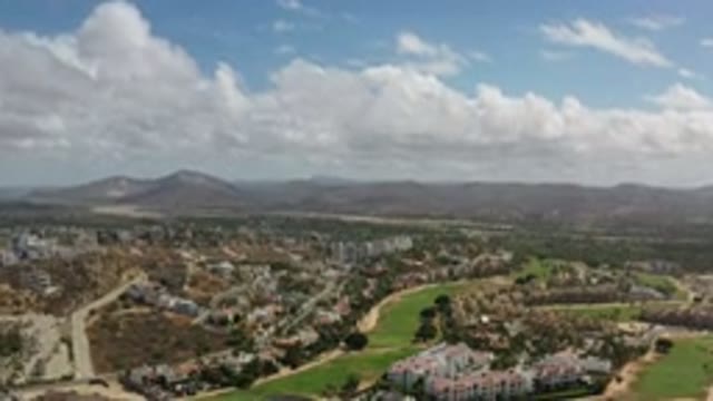LOS CABOS MEXICO-2020: Town Below And A Cloudy Sky Above And Mountains In The Distance