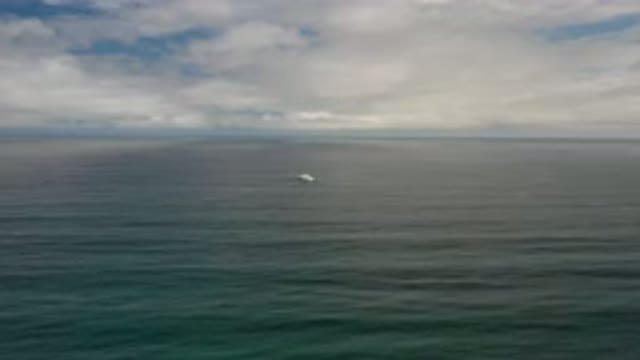 LOS CABOS MEXICO-2020: Calm Ocean Waves On A Slightly Cloudy Sunny Day With A Small Boat In Distance